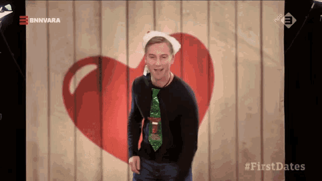 a man wearing a santa hat and tie is dancing in front of a heart on a wooden wall