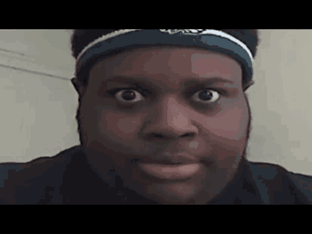 a man is wearing a headband and making a funny face .