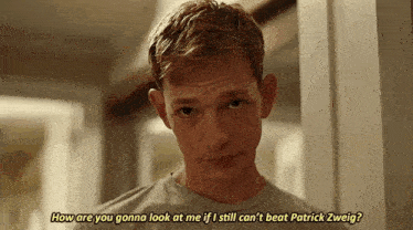 a young man is standing in a hallway and talking to another man .