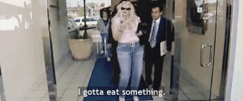 a woman is walking through a doorway with the words `` i gotta eat something '' above her .