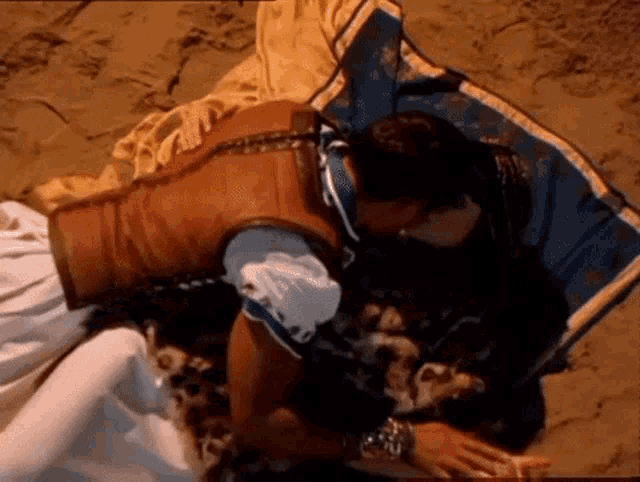 a man and a woman are kissing on a beach .