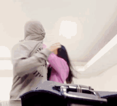 a man wearing a hoodie that says " all " is holding a woman 's hair