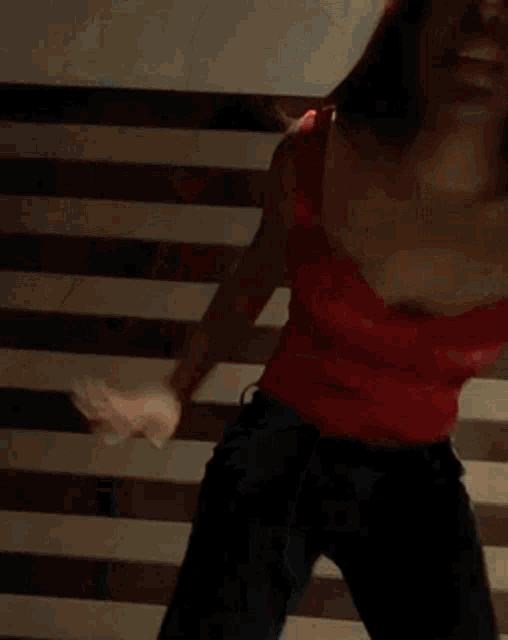 a woman in a red top and blue jeans is dancing on stairs .