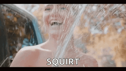 a naked woman is taking a shower in front of a car with the words `` squirt '' written on the screen .