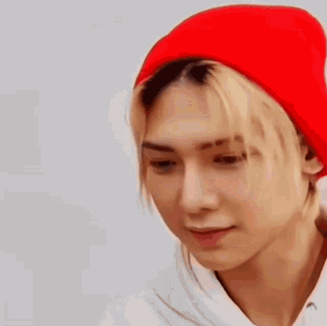 a young man wearing a red beanie and a white hoodie