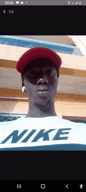 a man wearing a nike shirt and a red hat looks at the camera