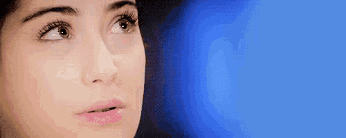 a close up of a woman 's face with a blue background and looking up .