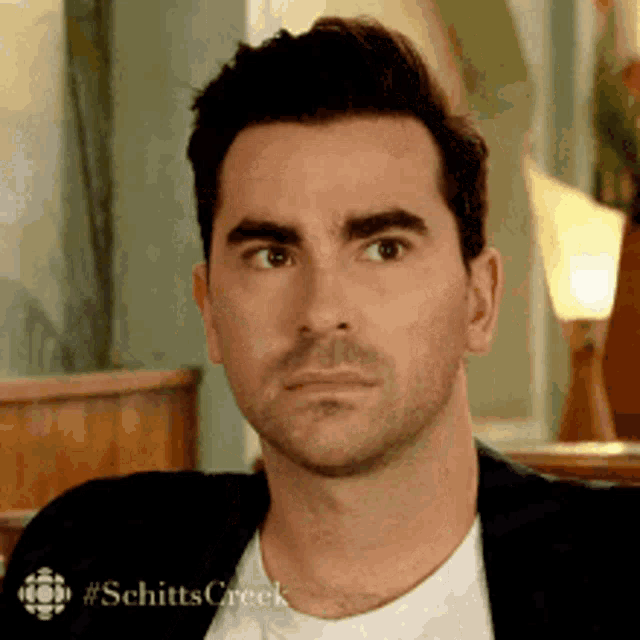 a man in a suit and white shirt is making a funny face while sitting in a chair .