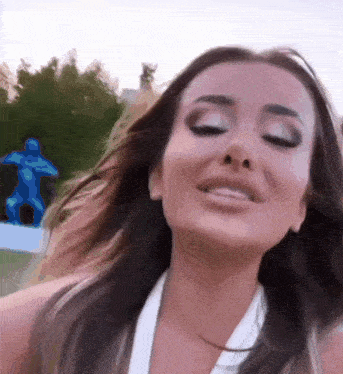 a close up of a woman 's face with a blue statue behind her
