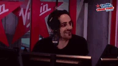 a man wearing headphones is smiling in front of a microphone .