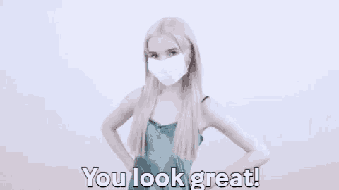 a woman wearing a mask is standing with her hands on her hips and says `` you look great '' .