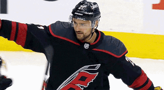 a hockey player wearing a black and red jersey with the letter r on it