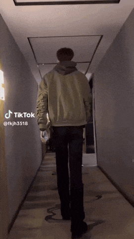 a man is walking down a hallway with tiktok written on the bottom of the video