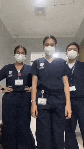 a group of nurses wearing masks and scrubs are standing next to each other .