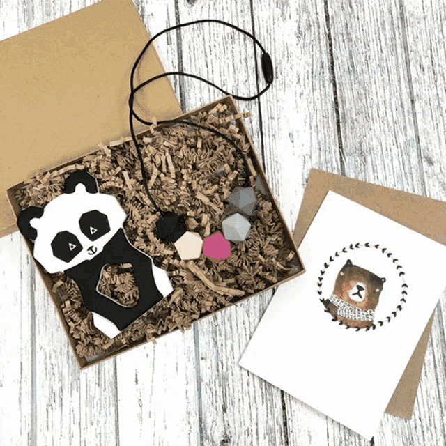 a panda teething toy is in a box next to a card with a picture of a bear on it