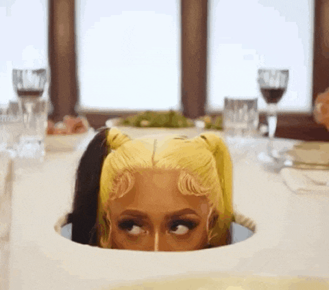 a woman with blonde hair is looking out of a hole in a table .