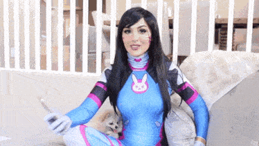 a woman in a blue and pink costume is sitting on a couch with a small dog .