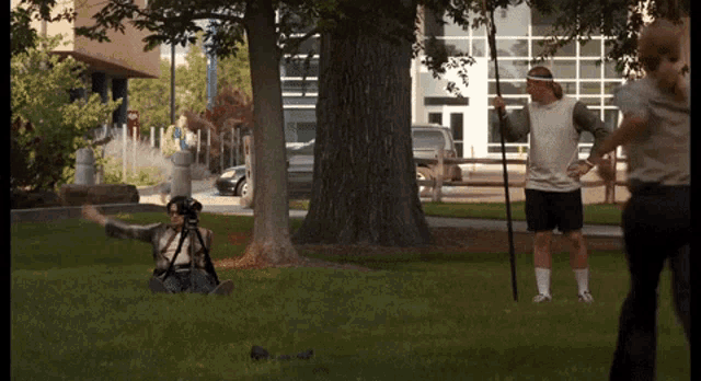 a man sitting on the grass taking a picture of another man