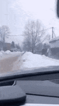 a car driving down a snowy road with trees in the background