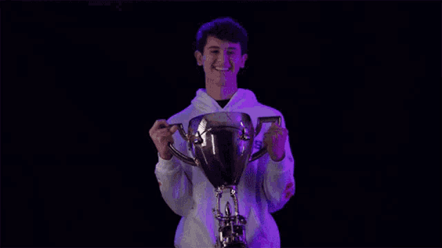 a young man in a white hoodie is holding a trophy in his hands