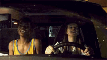a man and a woman are driving a car and laughing