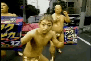 a group of naked men are walking down a street with a sign that says 12 on it