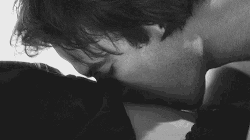 a black and white photo of a man kissing a woman on the neck .