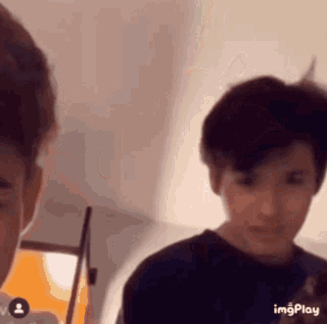 two young men are standing next to each other in a room and looking at the camera .