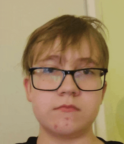 a young boy wearing glasses is making a face .