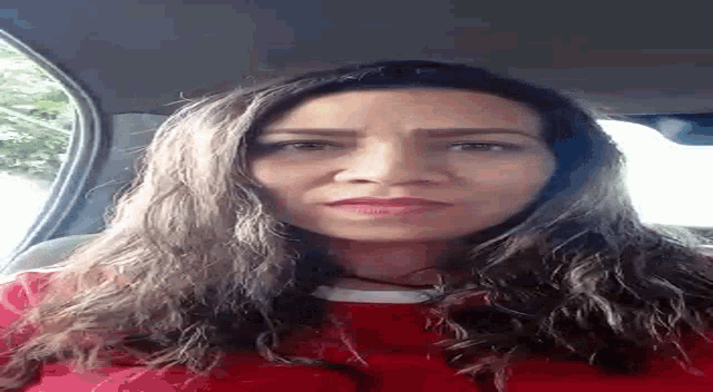 a woman is sitting in the back seat of a car looking at the camera .