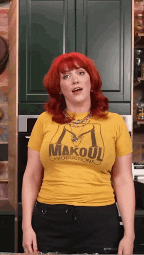 a woman with red hair wears a yellow makoul productions t-shirt