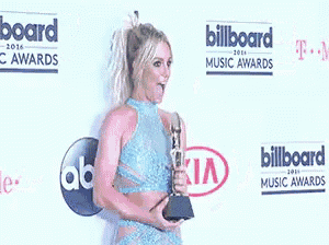 a woman is holding a trophy in front of a billboard sign