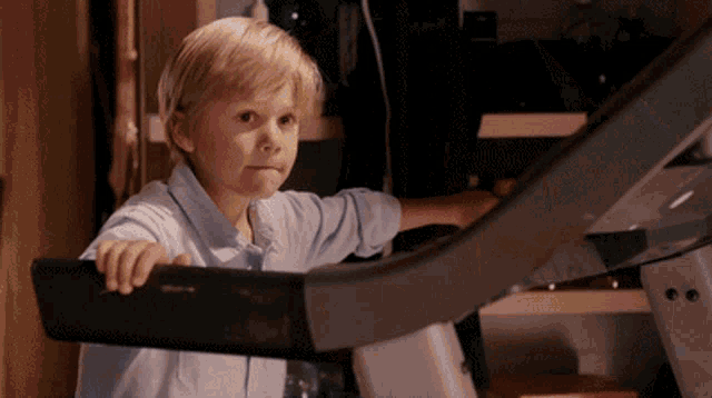 a young boy is sitting on a treadmill that says lg on the side