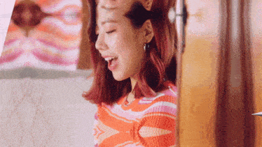 a woman with red hair is wearing a striped sweater and earrings .