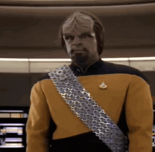 a man in a yellow and black uniform with a silver belt around his waist is standing in a room .