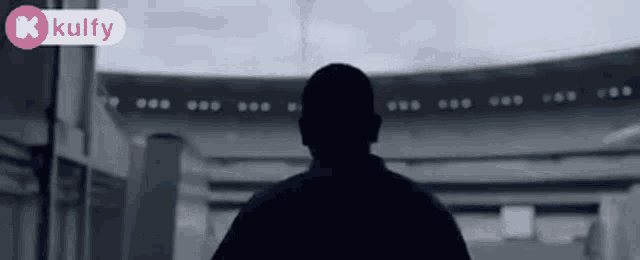 a man is walking into a stadium with a kolfy logo in the corner .