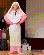 a man is wrapped in a pink and white blanket and standing on a stage .