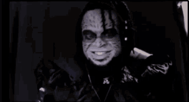 a man with purple glasses and a black jacket is smiling and looking at the camera .