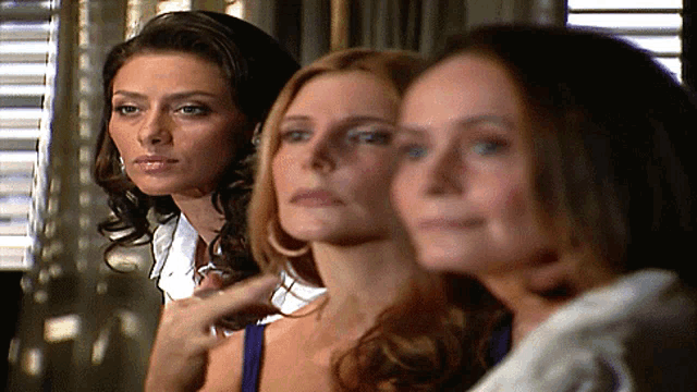 three women are standing next to each other in a room