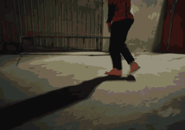 a person 's shadow is cast on the ground while walking