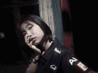 a young woman in a black shirt is taking a selfie with her phone .
