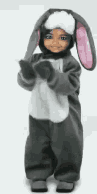 a little girl dressed in a bunny costume is standing in front of a white background .
