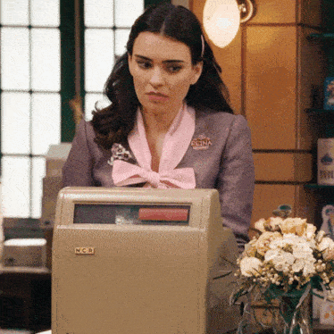 a woman behind a n.c.a. machine with a bouquet of flowers in front of her