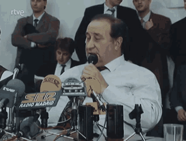 a man speaking into a microphone with a sign that says radio madrid on it