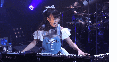 a girl is playing a keyboard that says roland on the side