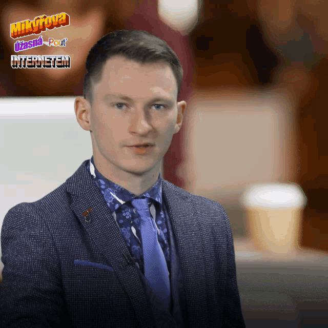 a man in a suit and tie stands in front of a sign that says mikyrova usnad pout