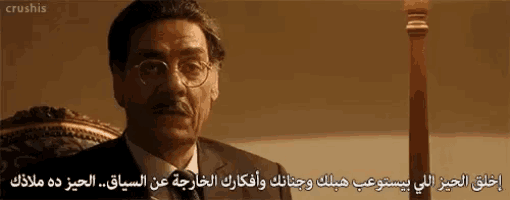a man with glasses and a mustache is sitting in a chair with arabic writing on it .