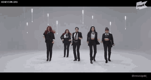 a group of women in tuxedos are dancing in front of a white background .