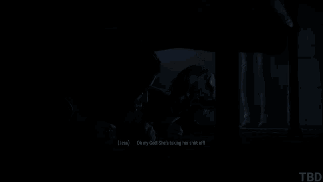 a man is laying on a bed in a dark room and talking to another man .