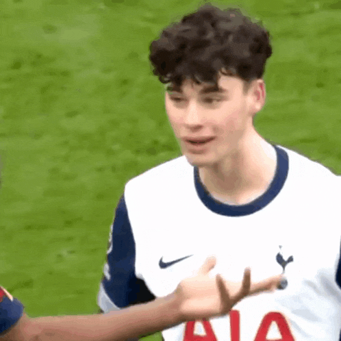 a young soccer player is giving a thumbs up to another player on a field .
